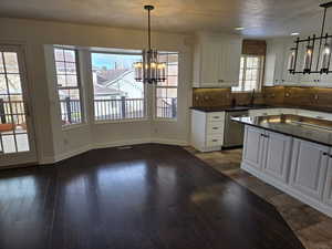 Kitchen with dishwasher, decorative light fixtures, white cabinetry, and a healthy amount of sunlight