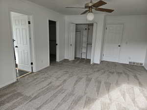 Master bedroom with carpet floors, two closets, ceiling fan, and ornamental molding