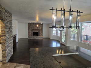 Unfurnished living room with a fireplace, a textured ceiling, a wealth of natural light, and dark wood-type flooring