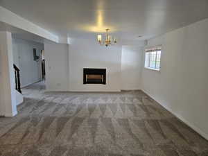 Unfurnished living room with carpet and an inviting chandelier