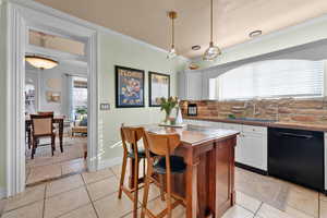 Kitchen featuring dishwasher, white cabinets, a kitchen island, and sink