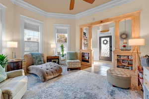 Living area featuring ceiling fan, ornamental molding, and light tile patterned flooring