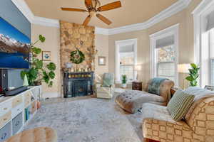 Tiled living room with ceiling fan, a fireplace, and ornamental molding