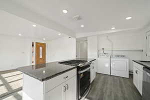 Kitchen featuring white cabinetry, separate washer and dryer, dark hardwood / wood-style floors, a kitchen island, and appliances with stainless steel finishes