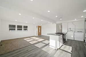 Kitchen featuring stainless steel range with gas cooktop, dark hardwood / wood-style flooring, separate washer and dryer, and white cabinets