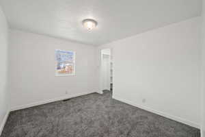 Carpeted spare room featuring a textured ceiling