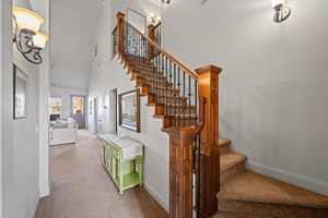 Stairway featuring carpet flooring and high vaulted ceiling