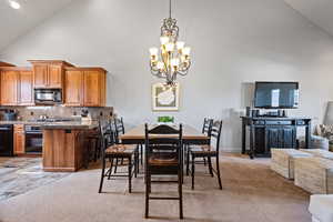 Dining room featuring light carpet, high vaulted ceiling, and a chandelier