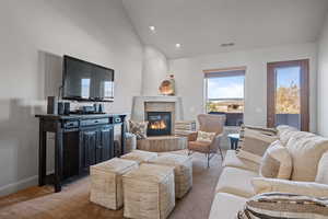 Living room featuring a fireplace, light carpet, and vaulted ceiling