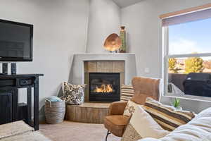 Living room with carpet flooring and a tiled fireplace