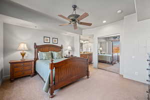 Bedroom featuring ceiling fan, a closet, light colored carpet, and ensuite bath