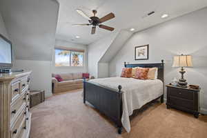 Carpeted bedroom with ceiling fan and lofted ceiling