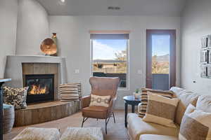 Living room with a tile fireplace, carpet flooring, and vaulted ceiling