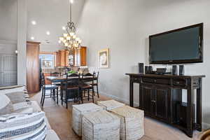 Dining room with a notable chandelier, light colored carpet, and a high ceiling