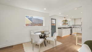 Dining area featuring beam ceiling, sink, and light hardwood / wood-style floors