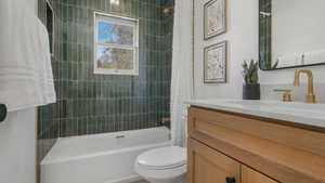 Full bathroom featuring shower / bathtub combination with curtain, vanity, and toilet