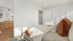 Bedroom with light wood-type flooring, sink, and ensuite bath