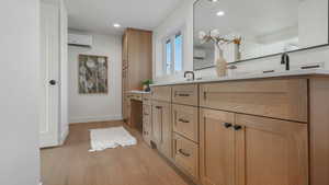 Bathroom featuring a wall unit AC, vanity, and hardwood / wood-style flooring