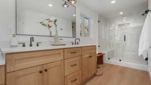 Bathroom with vanity, an enclosed shower, and wood-type flooring