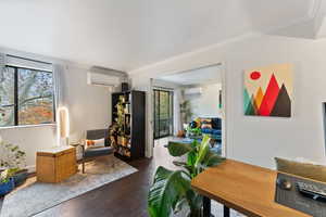 Interior space featuring a wall unit AC, crown molding, plenty of natural light, and dark hardwood / wood-style floors