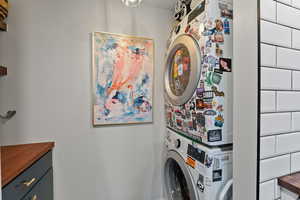 Washroom featuring cabinets and stacked washer and clothes dryer