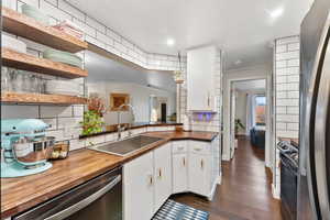 Kitchen featuring wooden counters, sink, dark hardwood / wood-style flooring, white cabinetry, and stainless steel appliances