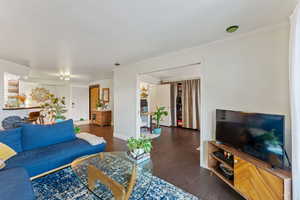 Living room with dark hardwood / wood-style floors and crown molding