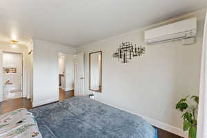 Bedroom featuring dark hardwood / wood-style flooring, ensuite bath, a wall mounted AC, and ornamental molding