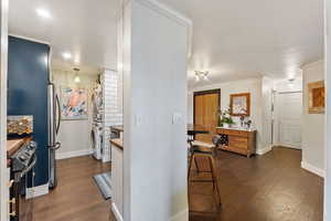 Kitchen with appliances with stainless steel finishes, butcher block countertops, dark hardwood / wood-style floors, and crown molding