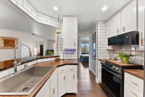 Kitchen featuring black appliances, wood counters, white cabinets, and sink