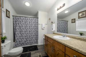 Full bathroom featuring vanity, shower / tub combo with curtain, crown molding, hardwood / wood-style flooring, and toilet