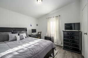 Bedroom with ornamental molding, light hardwood / wood-style floors, and lofted ceiling