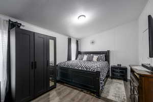 Bedroom with dark hardwood / wood-style flooring and a textured ceiling