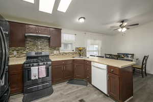 Kitchen featuring dishwasher, refrigerator, range with two ovens, light hardwood / wood-style floors, and kitchen peninsula