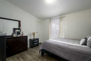 Bedroom with light hardwood / wood-style flooring, lofted ceiling, and crown molding