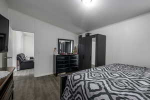 Bedroom featuring dark hardwood / wood-style flooring, ornamental molding, a textured ceiling, and vaulted ceiling