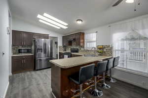 Kitchen featuring sink, light hardwood / wood-style flooring, decorative backsplash, kitchen peninsula, and stainless steel appliances