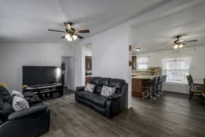 Living room featuring dark hardwood / wood-style flooring, vaulted ceiling, and ceiling fan