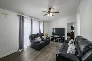 Living room featuring hardwood / wood-style floors, ceiling fan, ornamental molding, and vaulted ceiling