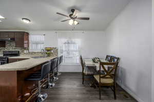 Kitchen featuring tasteful backsplash, a wealth of natural light, dark hardwood / wood-style flooring, and black range with gas cooktop