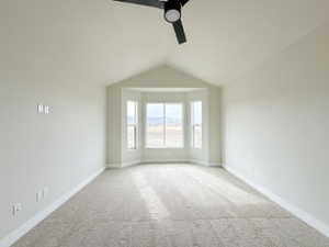 Unfurnished room with lofted ceiling, baseboards, a ceiling fan, and light colored carpet