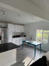Interior space with rail lighting, wood finished floors, and baseboards