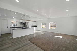 Kitchen featuring white cabinetry, dark hardwood / wood-style flooring, decorative backsplash, a kitchen island, and appliances with stainless steel finishes