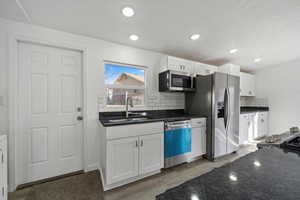 Kitchen with backsplash, sink, white cabinets, and stainless steel appliances