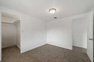 Unfurnished bedroom featuring dark carpet and a closet