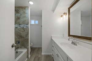 Full bathroom with vanity, toilet, wood-type flooring, and tiled shower / bath combo