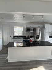 Kitchen with dark countertops, appliances with stainless steel finishes, and a sink