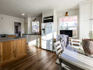 Kitchen with white refrigerator, white cabinets, sink,