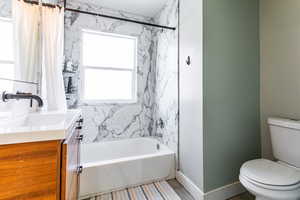 Full bathroom featuring vanity, toilet, and shower / tub combo with curtain