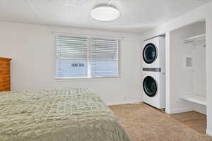 Carpeted bedroom with stacked washer and dryer